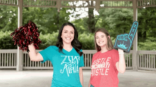 two women standing next to each other one wearing a shirt that says hustle cincinnati hustle