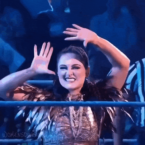 a woman is standing in a ring with her hands in the air .