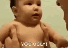 a baby is being held in a person 's arms and says `` you ugly '' .
