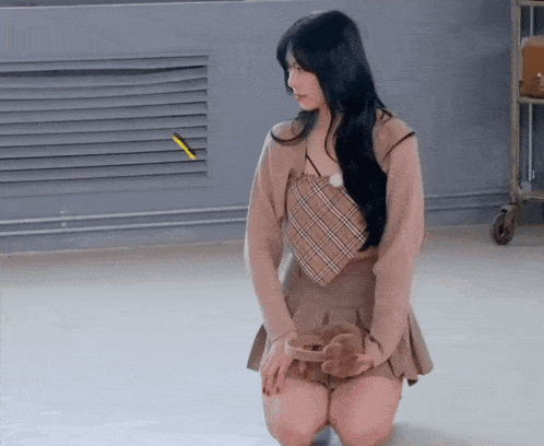 a woman in a plaid top and skirt is kneeling down on the floor