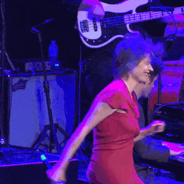 a woman in a red dress is dancing in front of a man playing a bass