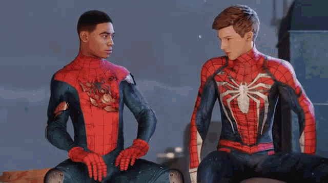 two men in spiderman costumes are standing next to each other and talking .