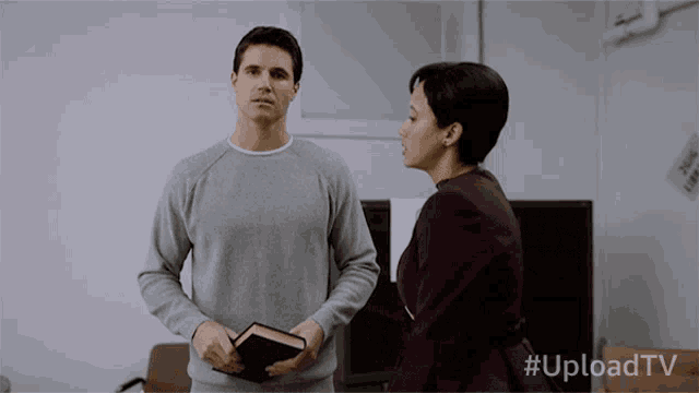 a man holding a book stands next to a woman with #uploadtv written on the bottom right