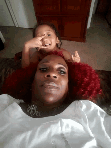 a woman with red hair is laying on a bed next to a child