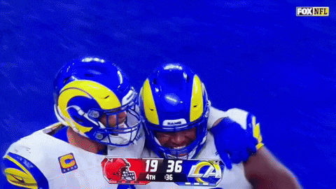 two rams players are hugging each other during a game