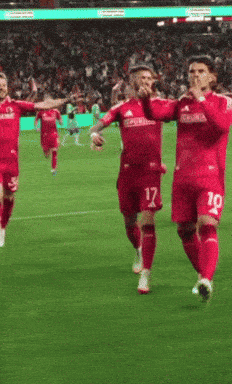 a group of soccer players wearing red jerseys with the numbers 17 and 10 running on the field