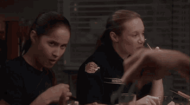 two female firefighters sit at a table drinking from glasses