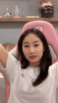 a girl is sitting in a pink chair with her arms outstretched