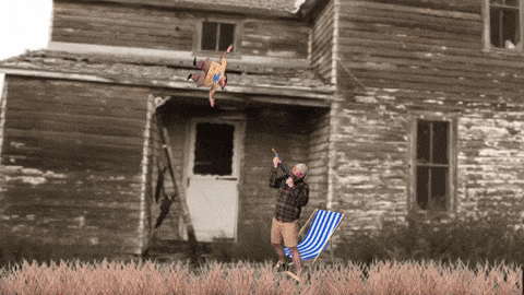 a man in a plaid shirt is standing in front of an old house