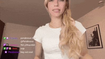 a woman in a white t-shirt is standing in front of a wall with a picture on it