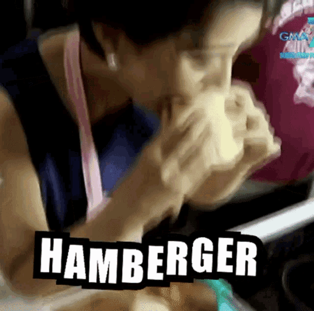 a woman is eating a hamburger in a blurry photo with the word hamburger above her