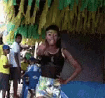 a woman in a black tank top and shorts is standing in front of a group of people .