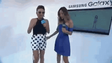 two women are standing next to each other in front of a sign that says samsung galaxy .