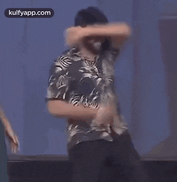 a man in a hawaiian shirt is dancing on stage .