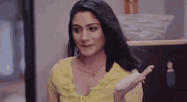 a woman in a yellow shirt is making a funny face while holding something in her hands .
