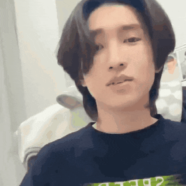 a young man with long hair is wearing a black t-shirt .