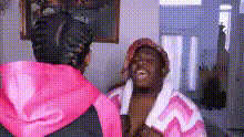 a woman in a pink hoodie is standing next to a man in a pink robe in front of a mirror .