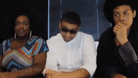 a man wearing sunglasses sits between two women with twitter written on the bottom left