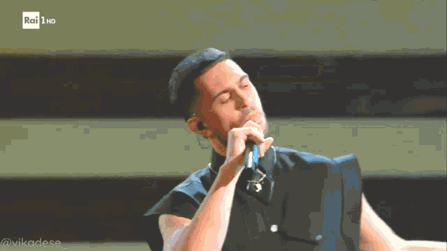 a man singing into a microphone with rai hd in the corner
