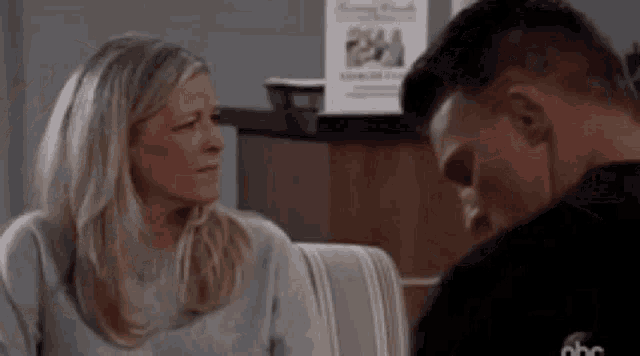 a man and a woman are sitting next to each other on a couch and looking at each other .