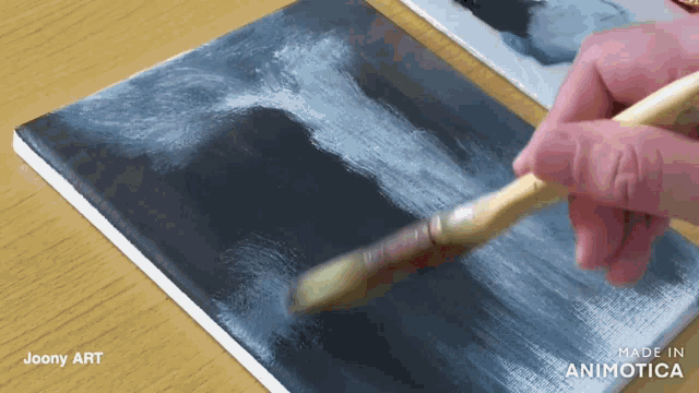 a person is painting on a piece of paper that says made in animotica on it