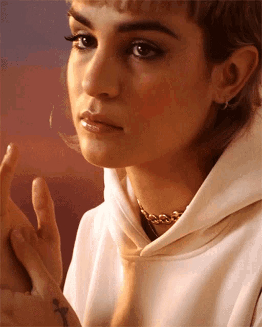 a close up of a woman 's face with a tattoo on her wrist