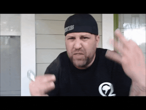 a man wearing a black shirt and a black beanie with the word fires on it is making a funny face
