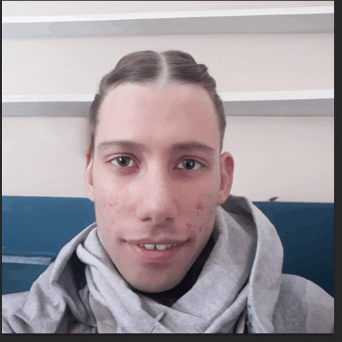 a young man wearing a grey scarf and a hoodie smiles for the camera