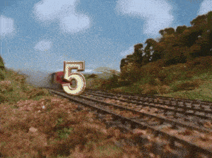 a train going down the tracks with the number 5 in the foreground