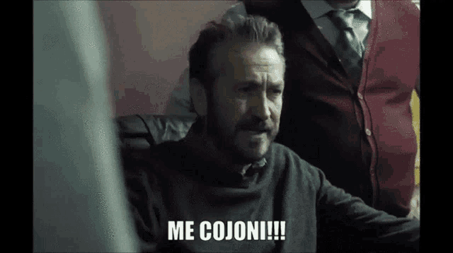 a man says me cojoni while sitting in a chair