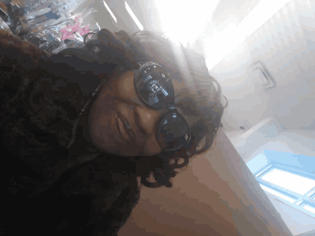 a woman wearing sunglasses and a fur coat smiles at the camera