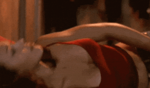 a woman in a red bra is laying on a bed with a man .