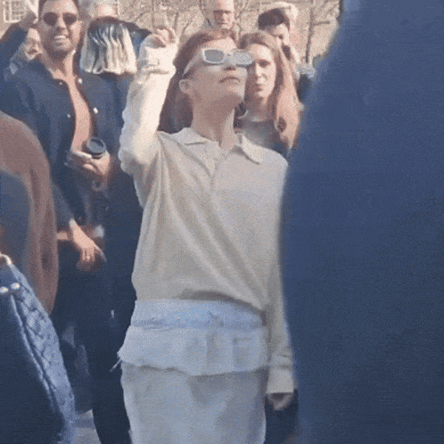 a woman wearing sunglasses is standing in a crowd of people