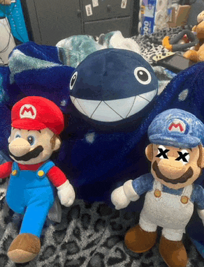 a stuffed mario is standing next to a stuffed shark