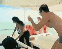 a man in a bikini is standing on a beach next to a woman in a bikini .