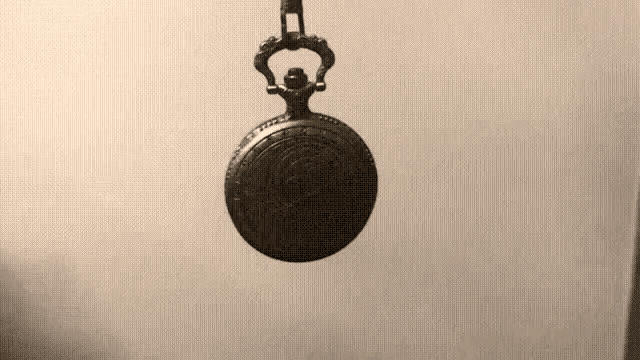a pocket watch is hanging from a chain on a wall