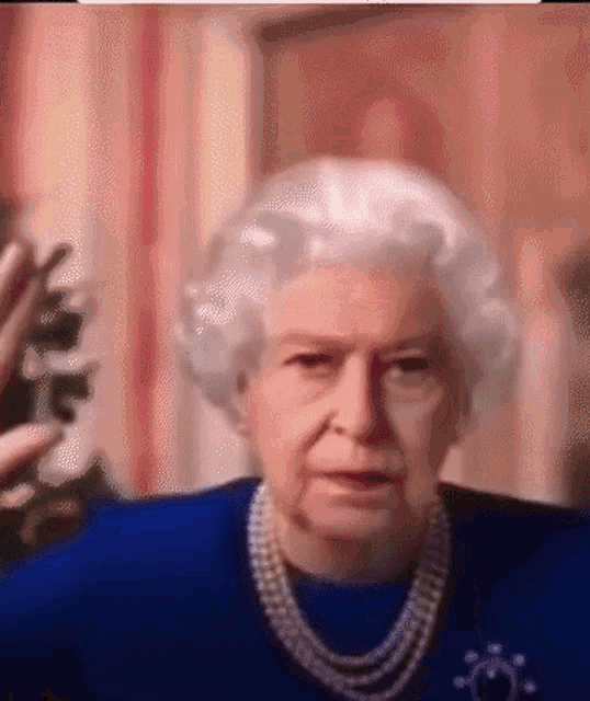 queen elizabeth ii is wearing a blue dress and pearls while talking on a video call .