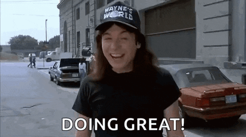 a man wearing a hat that says `` wayne 's world '' is standing on a street .