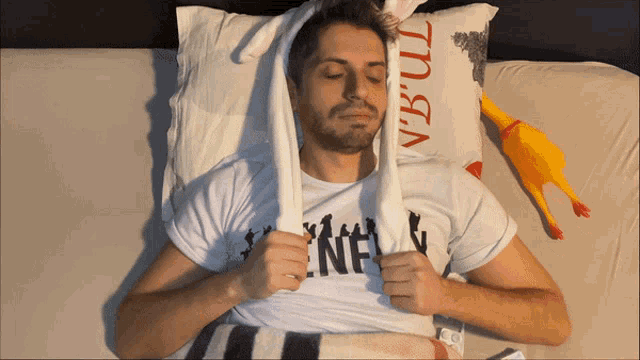 a man laying in bed with a towel over his head and a pillow that says vb-ul