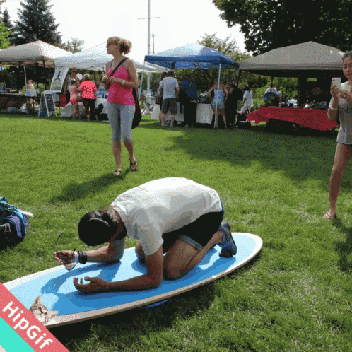 a man is kneeling on a surfboard with a hipgif watermark
