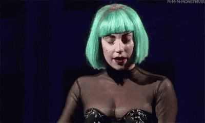 a woman wearing a green wig and a black top is standing in front of a blue background .