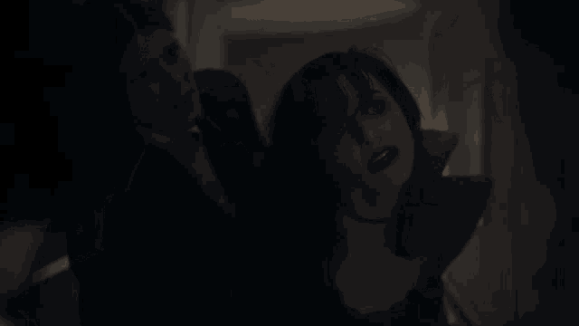 a man in a suit is holding a woman in a black dress