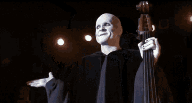 a bald man in a black robe is holding a pole and waving