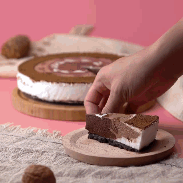 a person is taking a slice of cake from a wooden plate