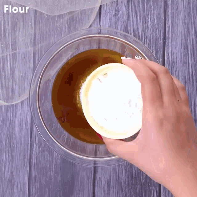 a bowl of flour is being poured into a bowl of liquid