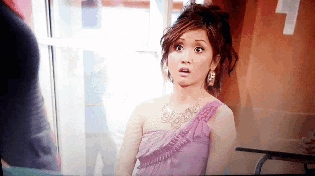 a woman in a purple dress with a necklace and earrings looks surprised