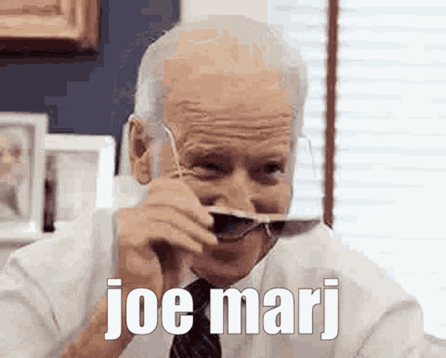 joe biden is wearing sunglasses and making a funny face while holding a spoon in his mouth .