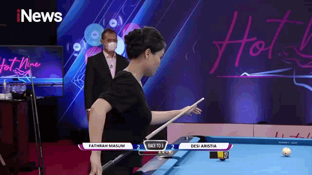a woman is holding a pool cue in front of a sign that says hot