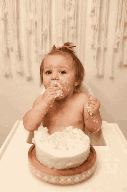 a baby in a high chair eating a cake with a spoon