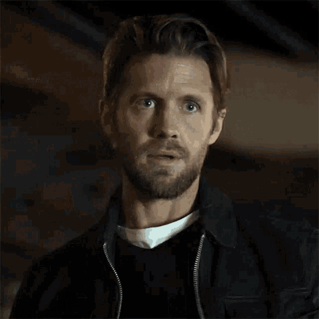 a man with a beard wears a black jacket